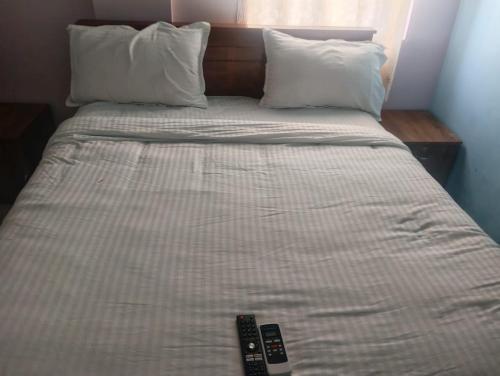 a bed with two remote controls on top of it at crown crest condos in Chengalpattu