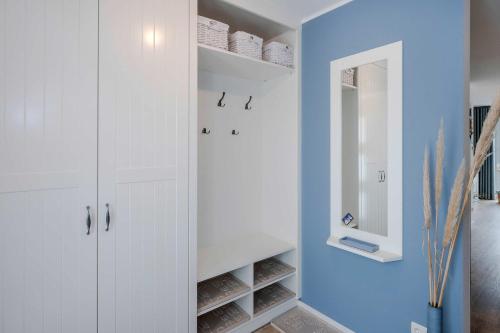a bathroom with white cabinets and a blue wall at Usedom-Idyll in Loddin