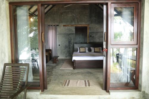 a bedroom with a bed and a sliding glass door at Aji fruit farm cottage peaceful lakeside farm stay with sunrise views 03 in Embilipitiya