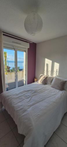 a bedroom with a large bed with a view of the ocean at Appartement T2 lac Léman in Publier