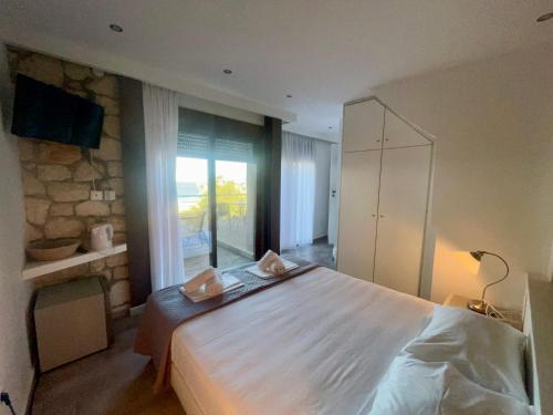a bedroom with a large white bed and a window at The Beach House - Apartments & Studios in Afitos