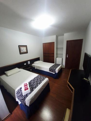 a room with two beds and a television in it at Pekin Palace Hotel in Araçatuba