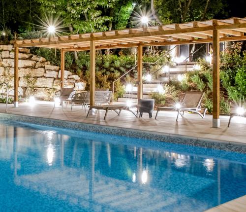 a pool at night with a pergola and chairs next to it at Guild Siena Senior Resort & Residence in Siena