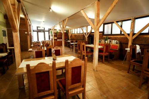 a restaurant with wooden tables and chairs and windows at Eged Panzió Eger in Eger