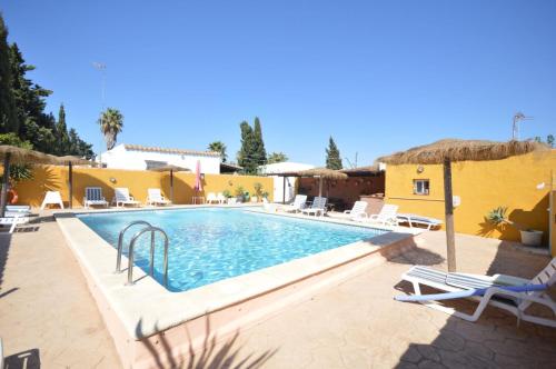 a swimming pool with chairs and a resort at Casa Samuel con piscina comunitaria y porche in Cádiz