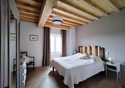 a bedroom with a white bed and wooden ceilings at Chambres D'hôtes Les Noisetiers in Saint-Martin-Lestra