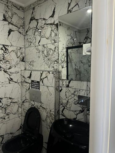 a bathroom with a black toilet and a marble wall at AsiaHOTEL in Bodrum City