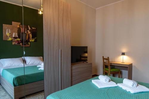 a bedroom with two beds and a desk and a television at Il Grappolo d'Oro Family - Appartamento in centro in Tortona