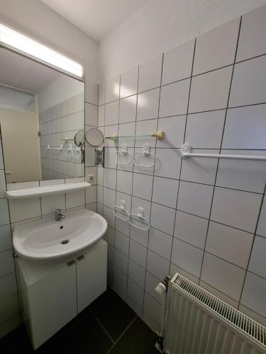 a white bathroom with a sink and a mirror at Huus Kompass - Familienurlaub mit Hund nahe am Nordseestrand in Butjadingen