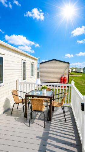 a patio with a table and chairs on a deck at Magic Caravan Camber Sands 221 in Camber