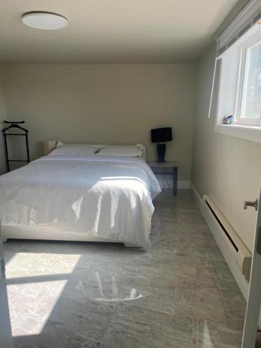 a bedroom with a white bed and a window at ocean view two bedroom suite in Oak Bay