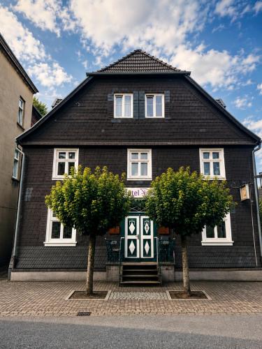 a black house with two trees in front of it at Hotel Pemü in Arnsberg