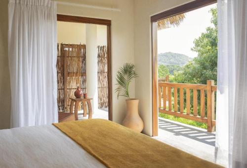 a bedroom with a bed and a sliding glass door with a porch at Angelique's Boutique Spa & Suites in La Unión