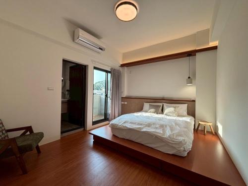 a bedroom with a bed and a chair and a window at White in Gukeng