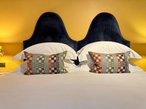 a bed with white pillows and a black headboard at East Beach Guest House in Littlehampton