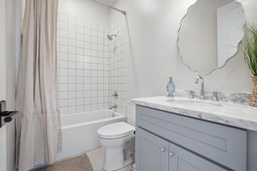 a white bathroom with a sink and a toilet at Spacious 3BR - Pool - Beach Nearby in Pass Christian