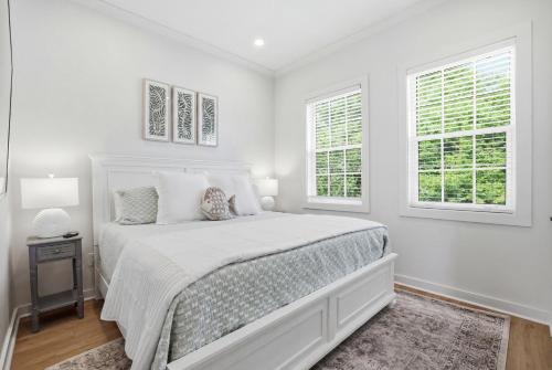 a white bedroom with a bed and two windows at Spacious 3BR - Pool - Beach Nearby in Pass Christian
