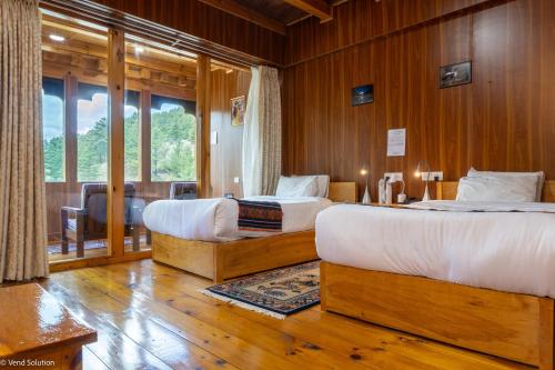 two beds in a room with wooden walls and wooden floors at Valley Resort in Jakar