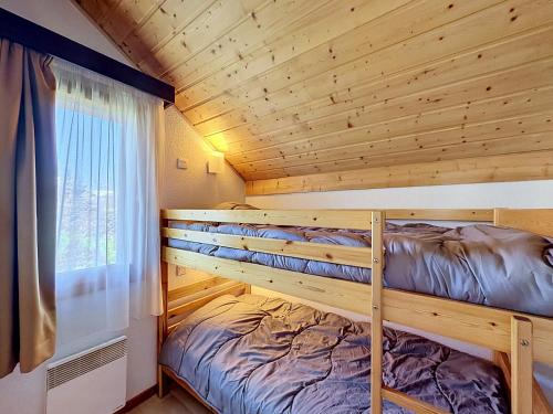 a bunk bed in a log cabin with a window at L'Eterlou by Mountain Collection Immobilier in Saint-Chaffrey