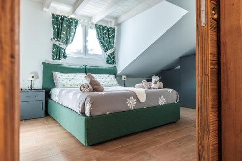 a bedroom with a green bed with stuffed animals on it at CHALET LAURA apricacasevacanze in Aprica