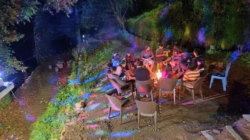a group of people sitting in chairs around a fire at Jibhi Dreams in Jibhi