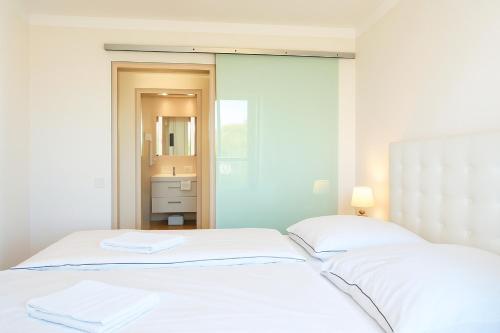 a white bedroom with two beds and a mirror at Mein-Zingst-Urlaub in Zingst