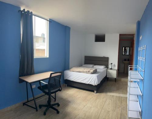 a bedroom with blue walls and a bed and a desk at Casa Totora in Huanchaco