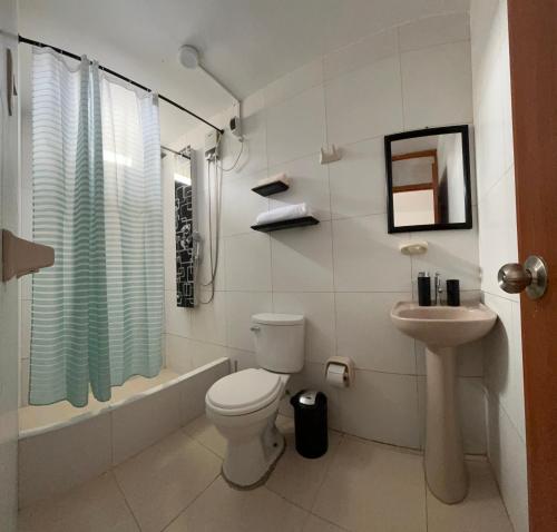 a white bathroom with a toilet and a sink at Casa Totora in Huanchaco