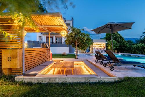 a swimming pool with two chairs and an umbrella at The Infinities - Premium Villa Alexandros in Kos