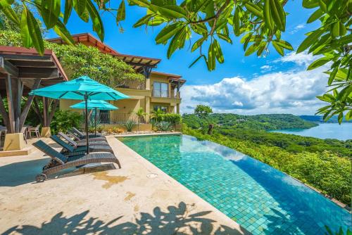 a swimming pool with chairs and an umbrella next to a house at Las Terrazas 7 Peninsula Papagayo in Nacascolo