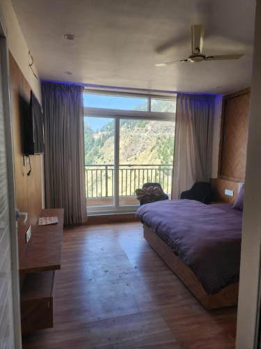 a bedroom with a bed and a large window at Hazy hill in Mussoorie