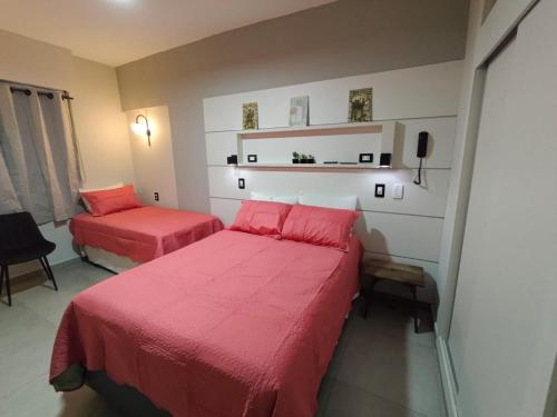 a bedroom with two beds with red sheets at Flat 113, Hotel Cavalinho Branco in Águas de Lindoia