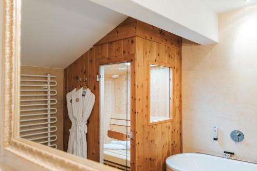 a bathroom with a mirror and a sink and a tub at Superior Hotel Schneider Ski-in & Ski-out in Obertauern