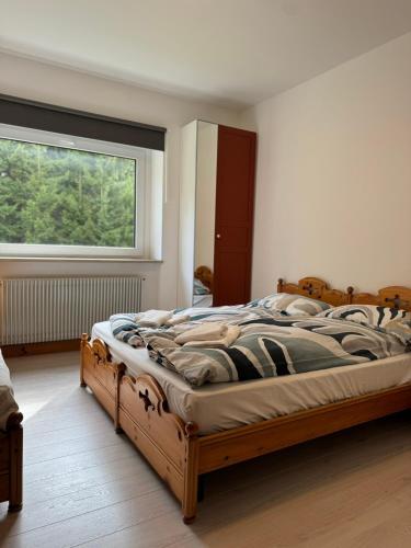 a bedroom with a large wooden bed with a window at Tra Neve e Lago Mountain Apartment in Sella Nevea