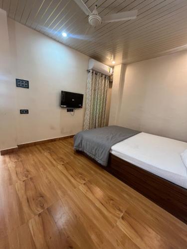 a room with two beds and a television in it at The Courtyard Stay in Patna