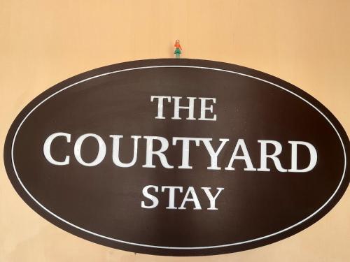 a black sign that says the courant stay at The Courtyard Stay in Patna