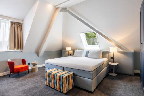 a bedroom with a bed and a red chair at Van der Valk Hotel Hilversum/ De Witte Bergen in Hilversum