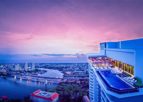 a building with a view of a river and a city at Avani Plus Riverside Bangkok Hotel in Bangkok