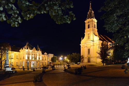 a large building with a clock tower at night at Hotel Zodiaco in Szekszárd