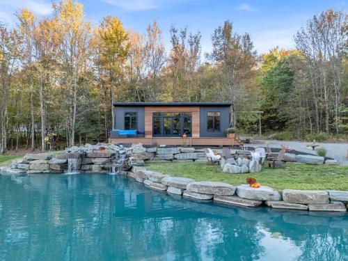 ein Haus mit einem Teich davor in der Unterkunft Tiny House on a Waterfall at Private Tiny Lake in Brackney