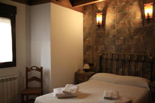 a bedroom with two beds and a stone wall at El Teñao in Navamorisca