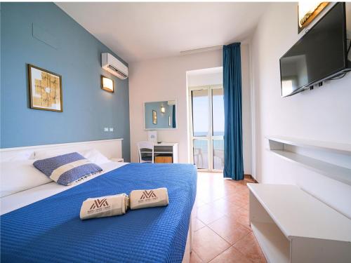 a blue and white bedroom with a bed and a tv at Hotel Club Perla in Casalabate