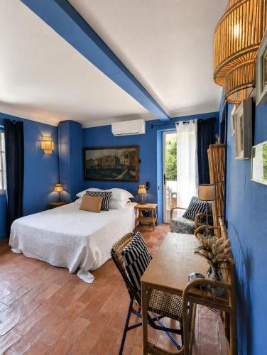 a bedroom with blue walls and a bed and a table at Le Jardin d'Emile in Cassis