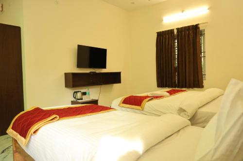 two beds in a room with a tv on the wall at Lumiere Point Yercaud in Yercaud