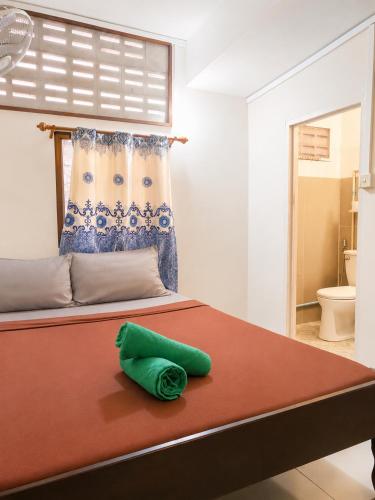 a bedroom with a bed with a green pillow on it at Soben Cafe Guesthouse & Restaurant in Siem Reap