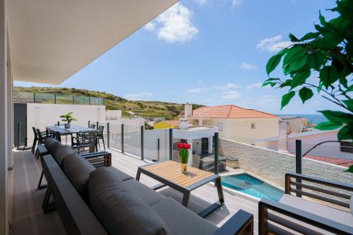 a balcony with a couch and a table with flowers on it at Eden Villa, with jacuzzi and ocean view in Casal do Cigano