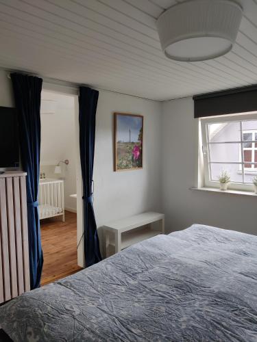a bedroom with a bed with blue curtains and a window at Like home Holiday House 9 A in Varde