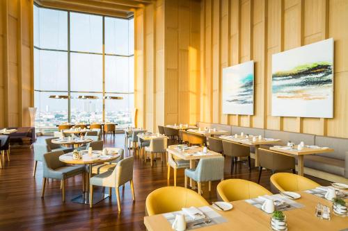 a restaurant with tables and chairs and large windows at Avani Plus Riverside Bangkok Hotel in Bangkok