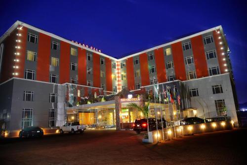a large building with cars parked in front of it at Grand Pela Hotel & Suites in Abuja