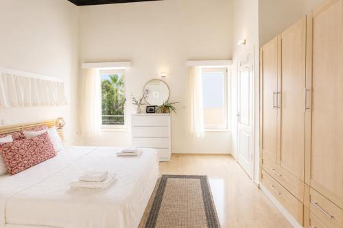 a white bedroom with a bed and a mirror at Villa Emilie in Kaş